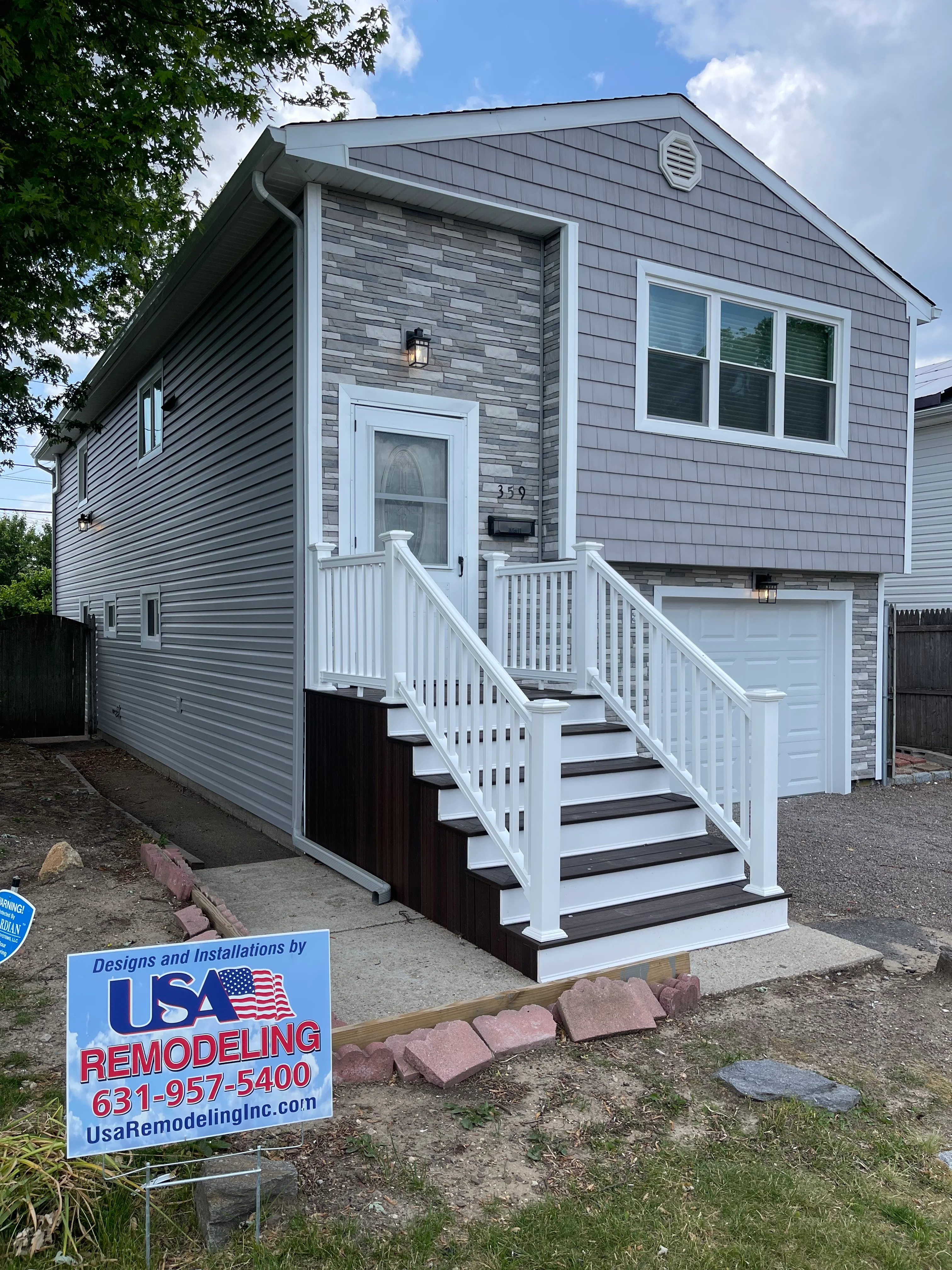 Modern gray and charcoal sided home with white railings and new garage door in Lindenhurst