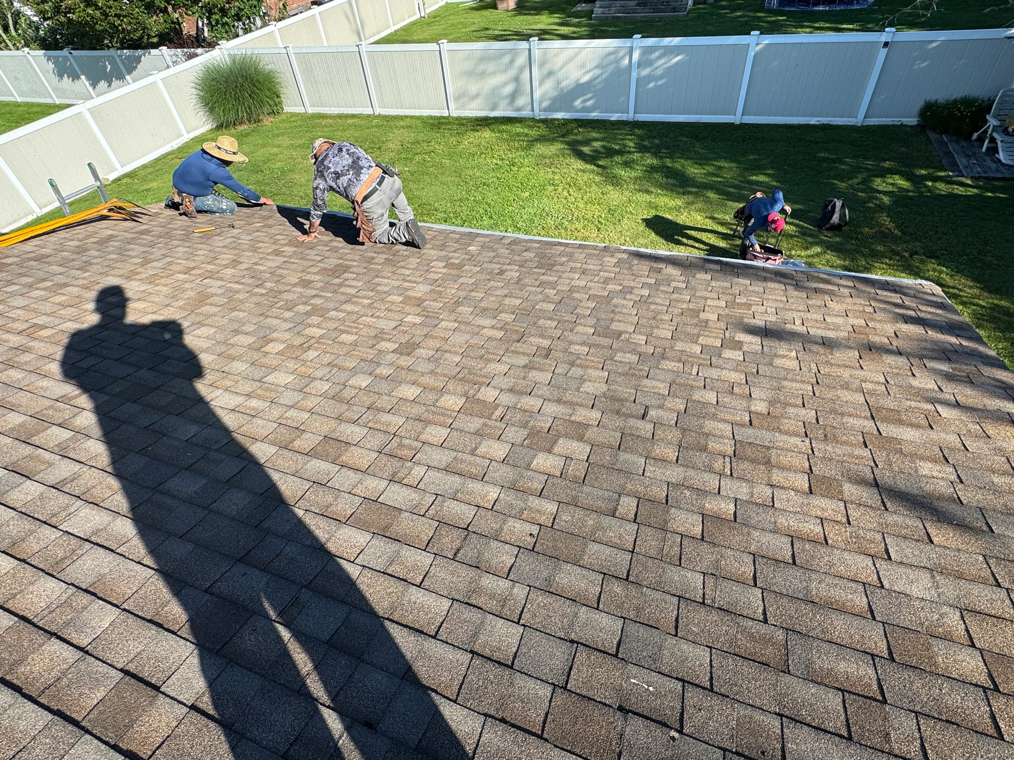 Roofers installing asphalt shingles on residential roof in Lindenhurst