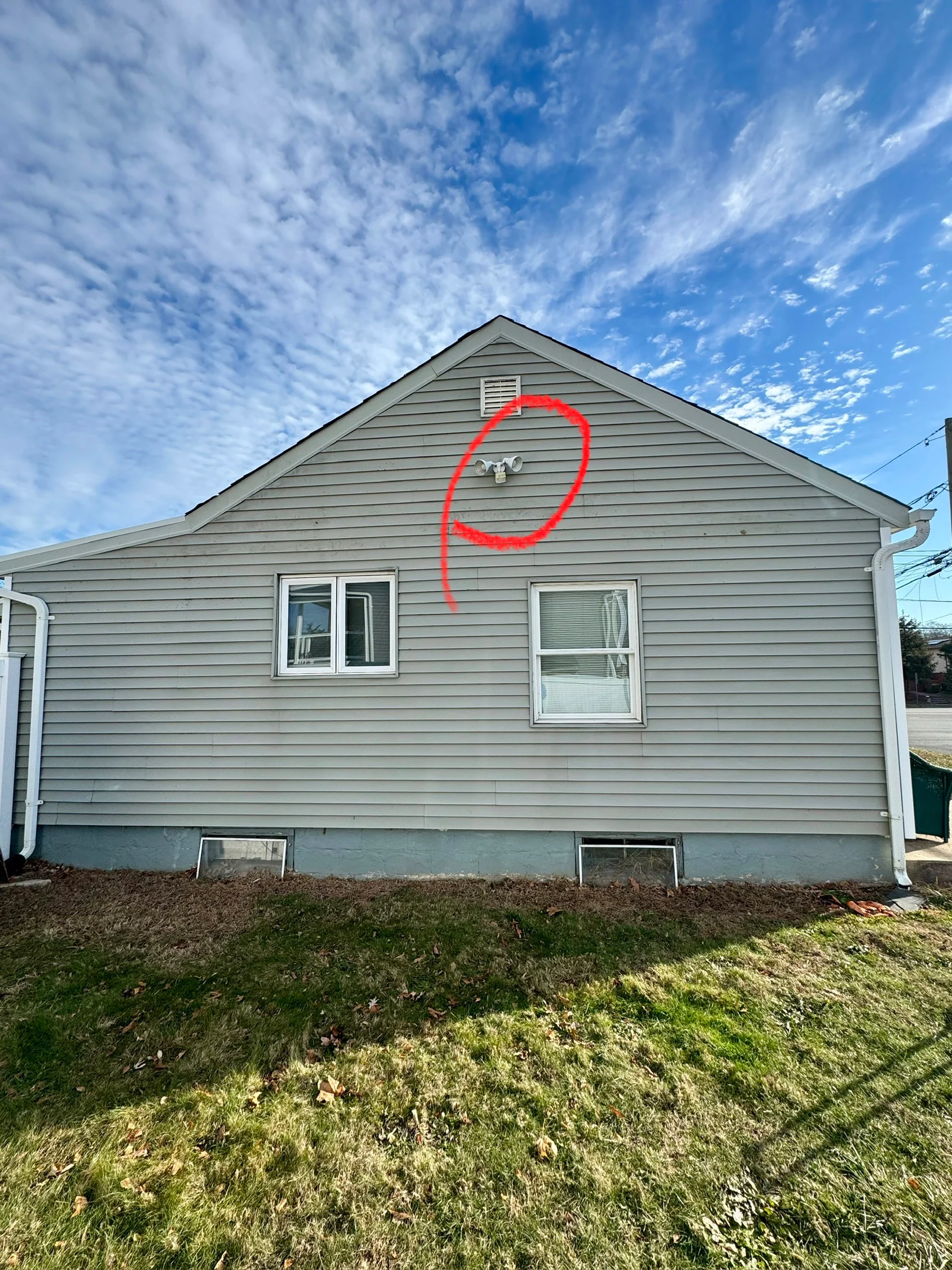 Light gray vinyl siding on residential home gable with two windows and white trim