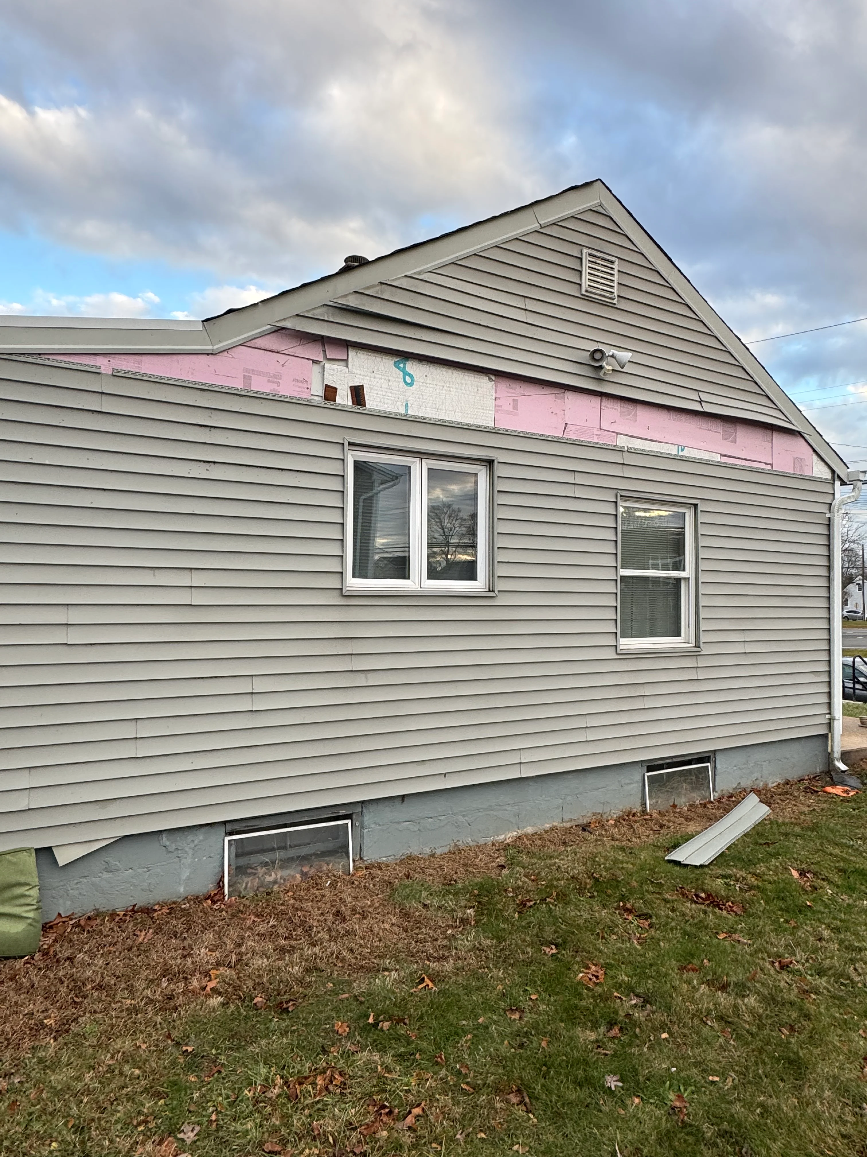 House with new gray vinyl siding and white windows during renovation in Lindenhurst