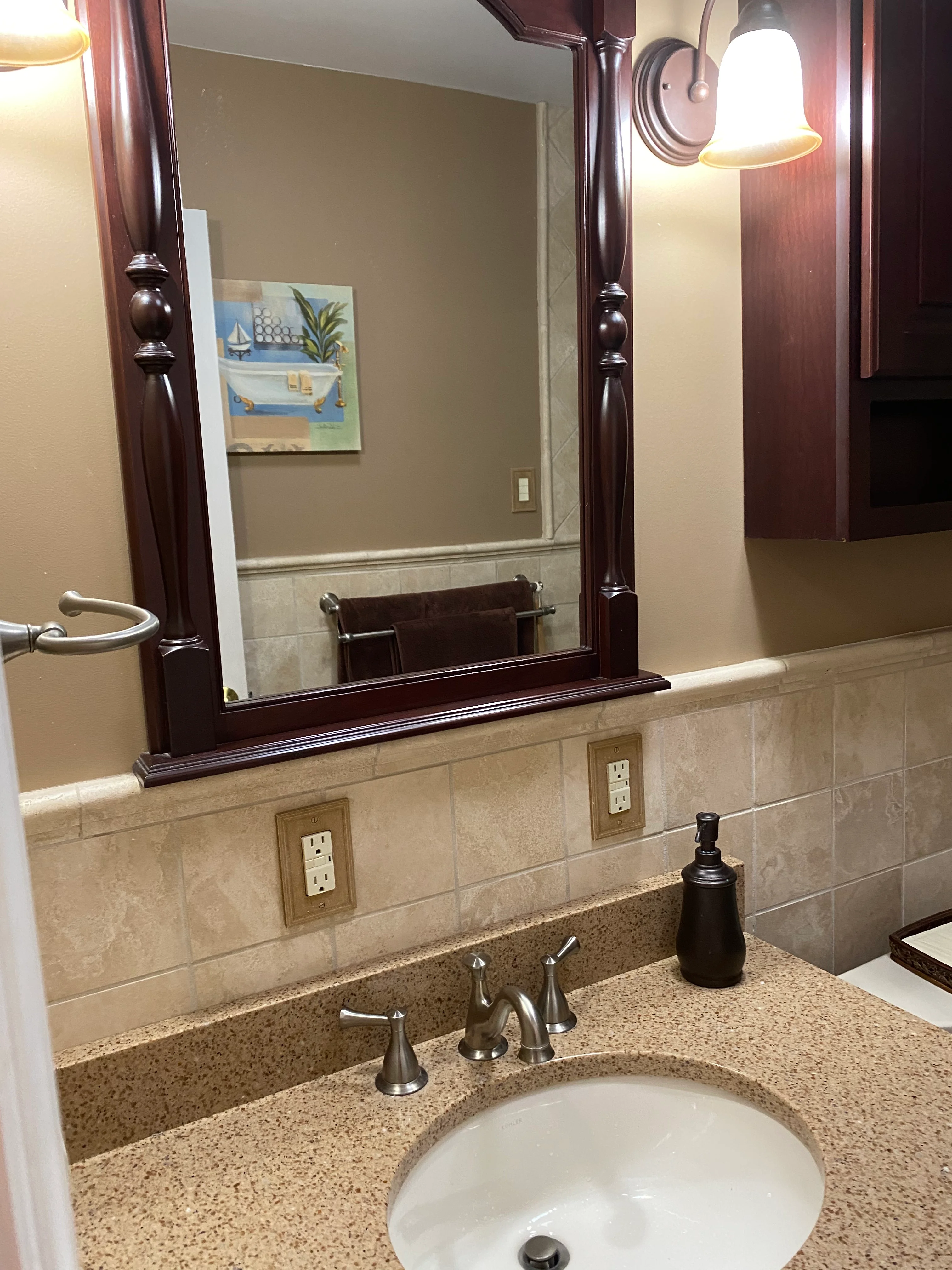 Bathroom vanity with quartz countertop, framed mirror, and tile backsplash