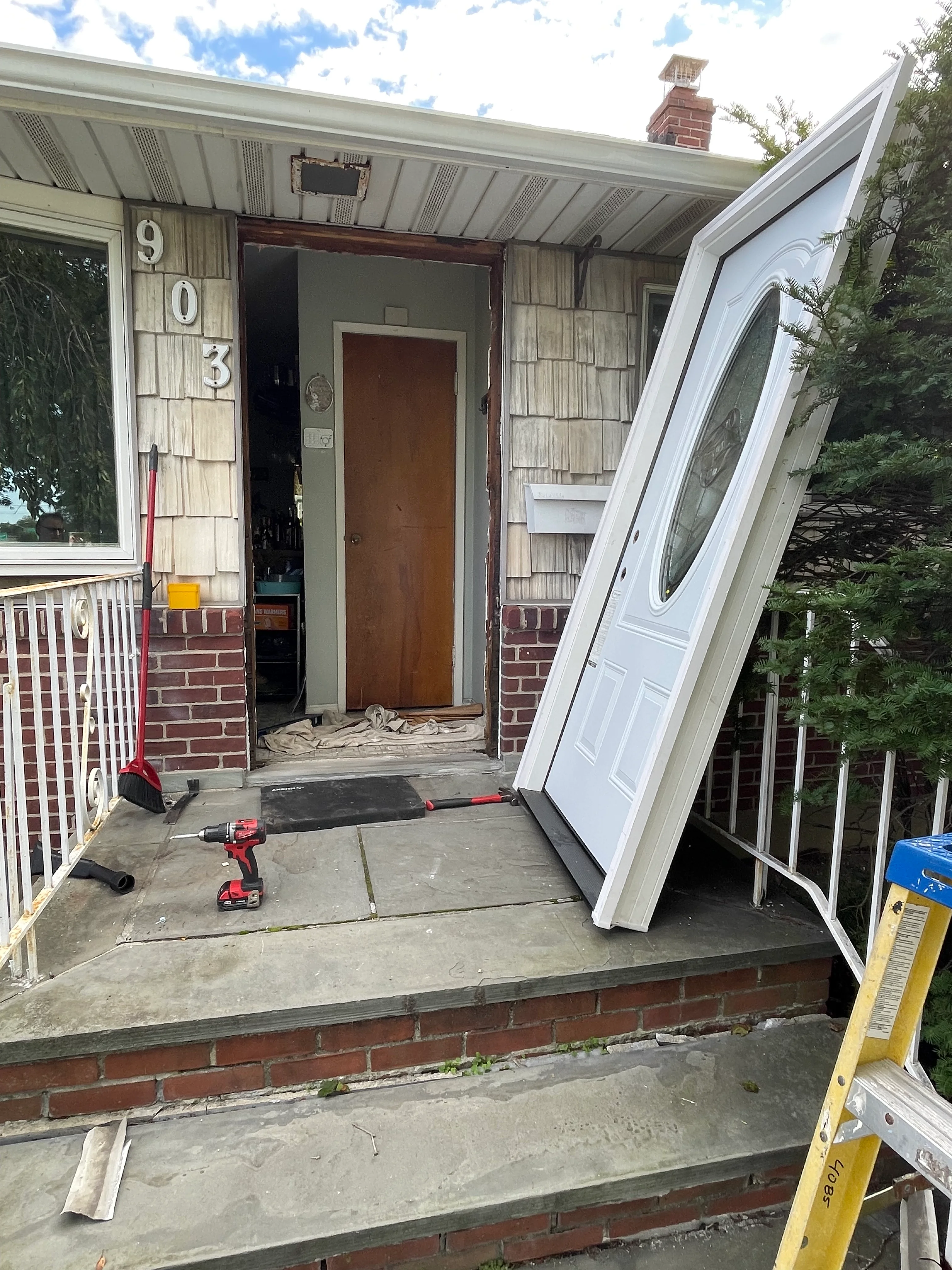 New white exterior door installation on brick and cedar shake home entryway