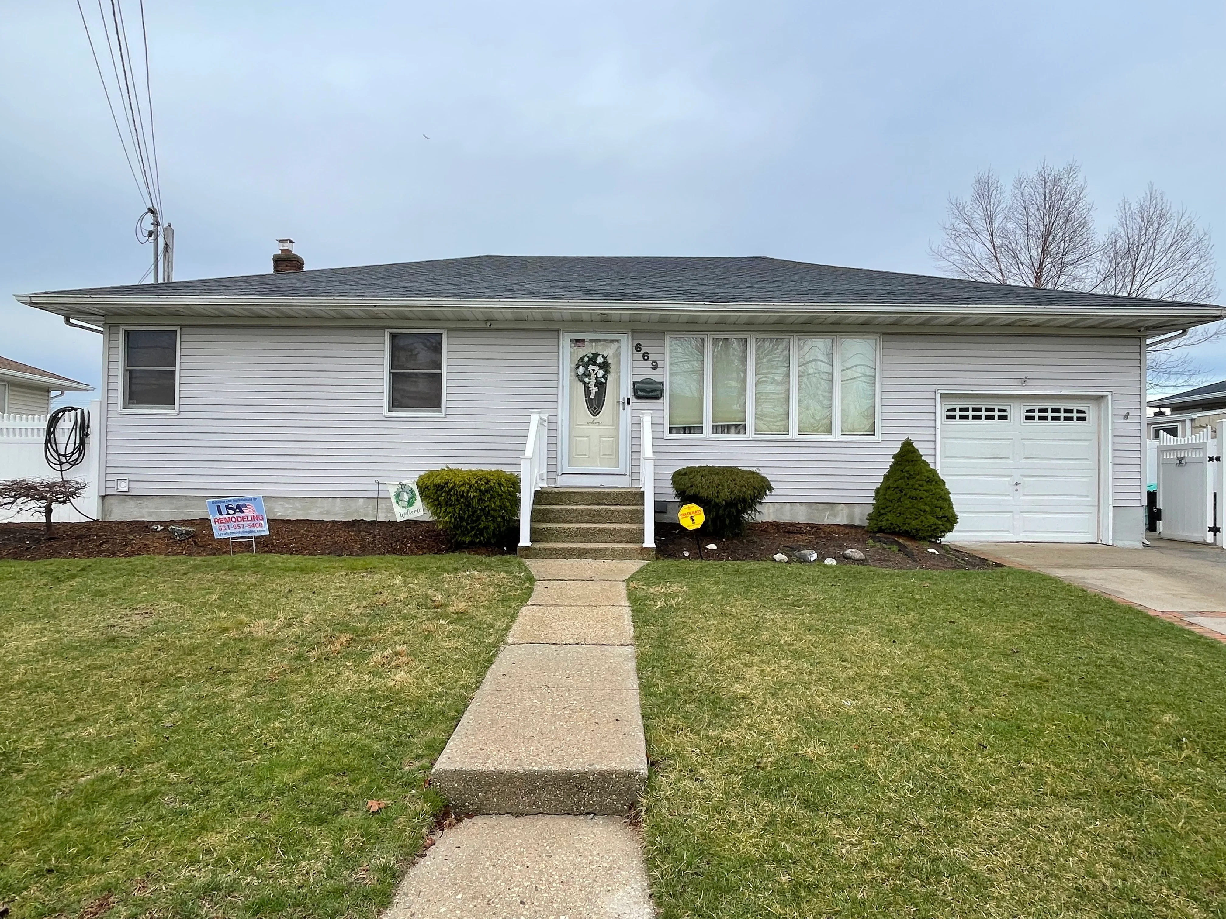 White ranch home with new siding, windows, and landscaping in Lindenhurst