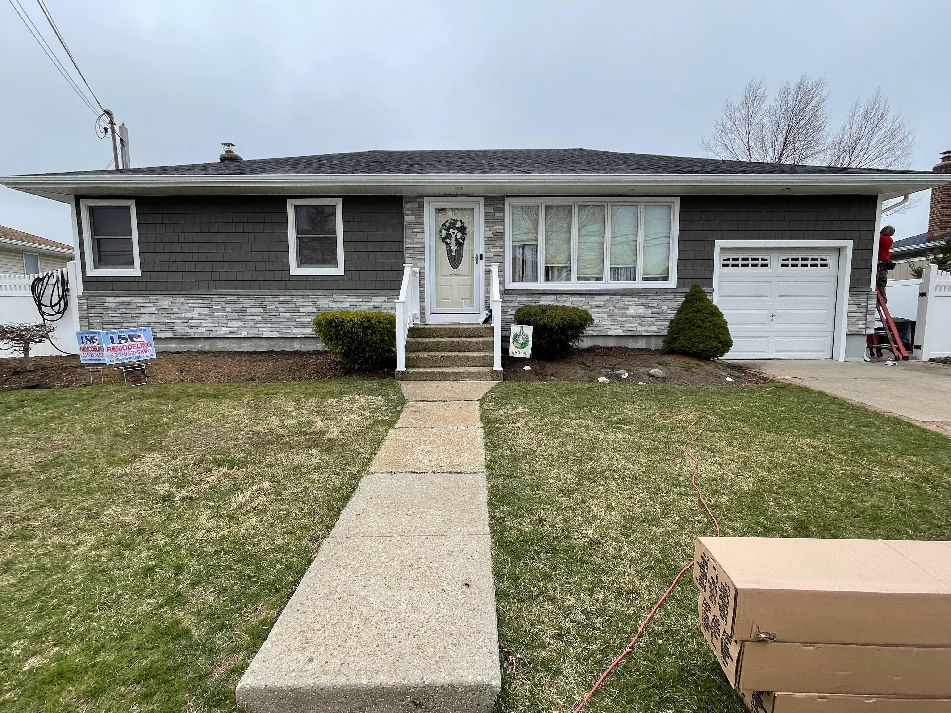 Renovated ranch home with gray composite siding, stone veneer base, white trim, and new windows