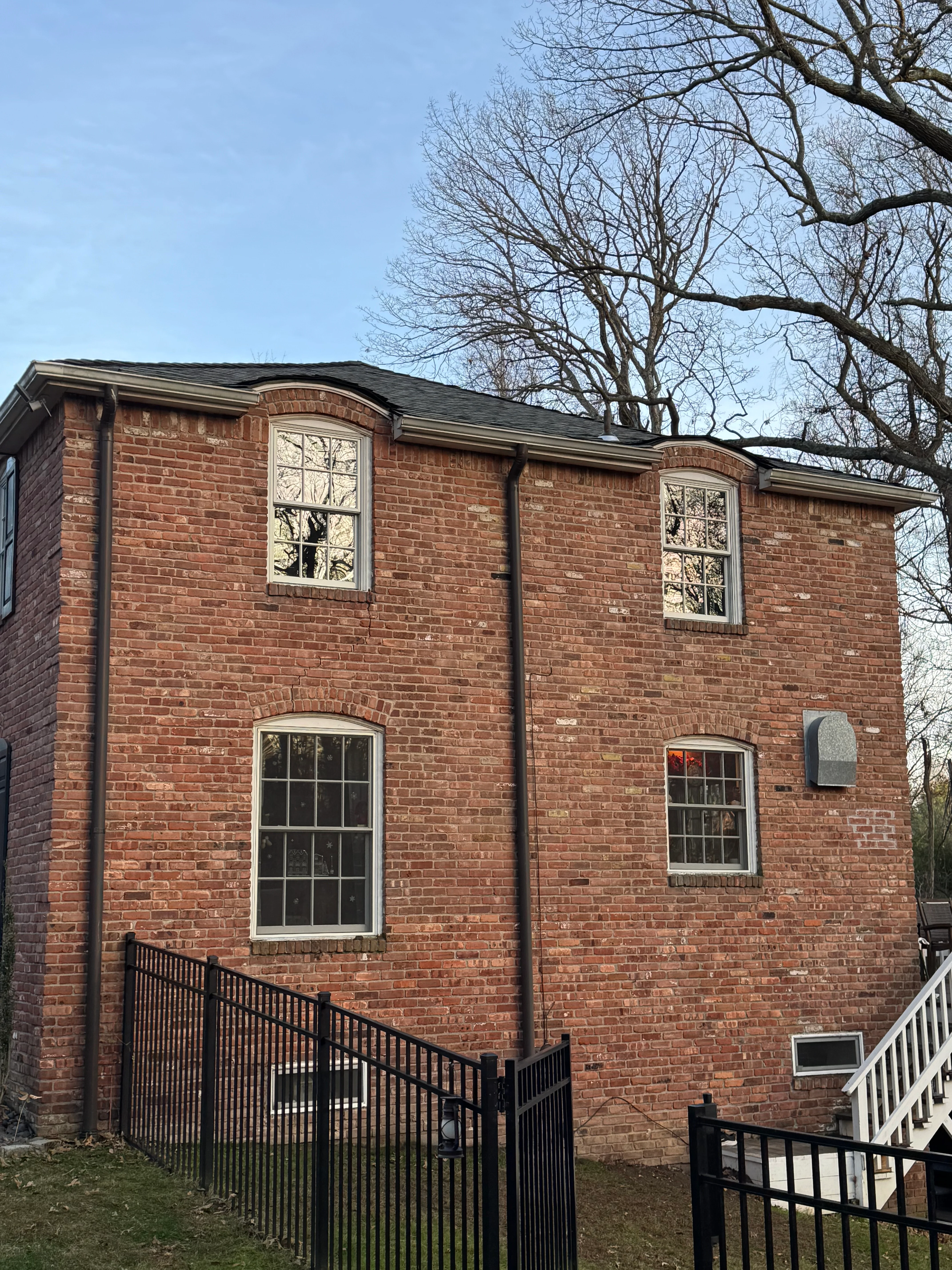 Two-story brick home with newly installed white-trimmed windows and black metal railings