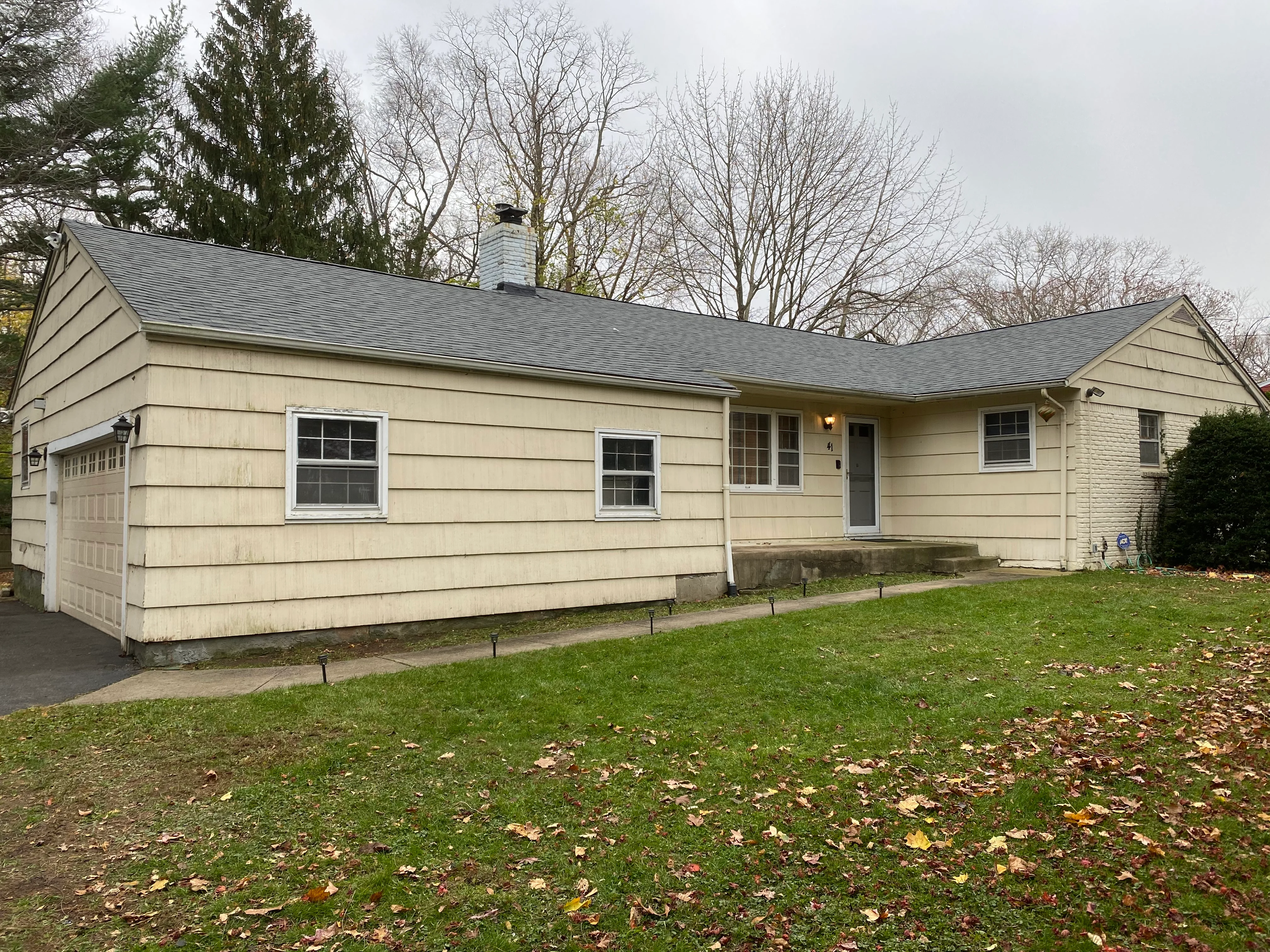 Cream-colored ranch home with new gray roof, vinyl siding, and updated windows in Lindenhurst