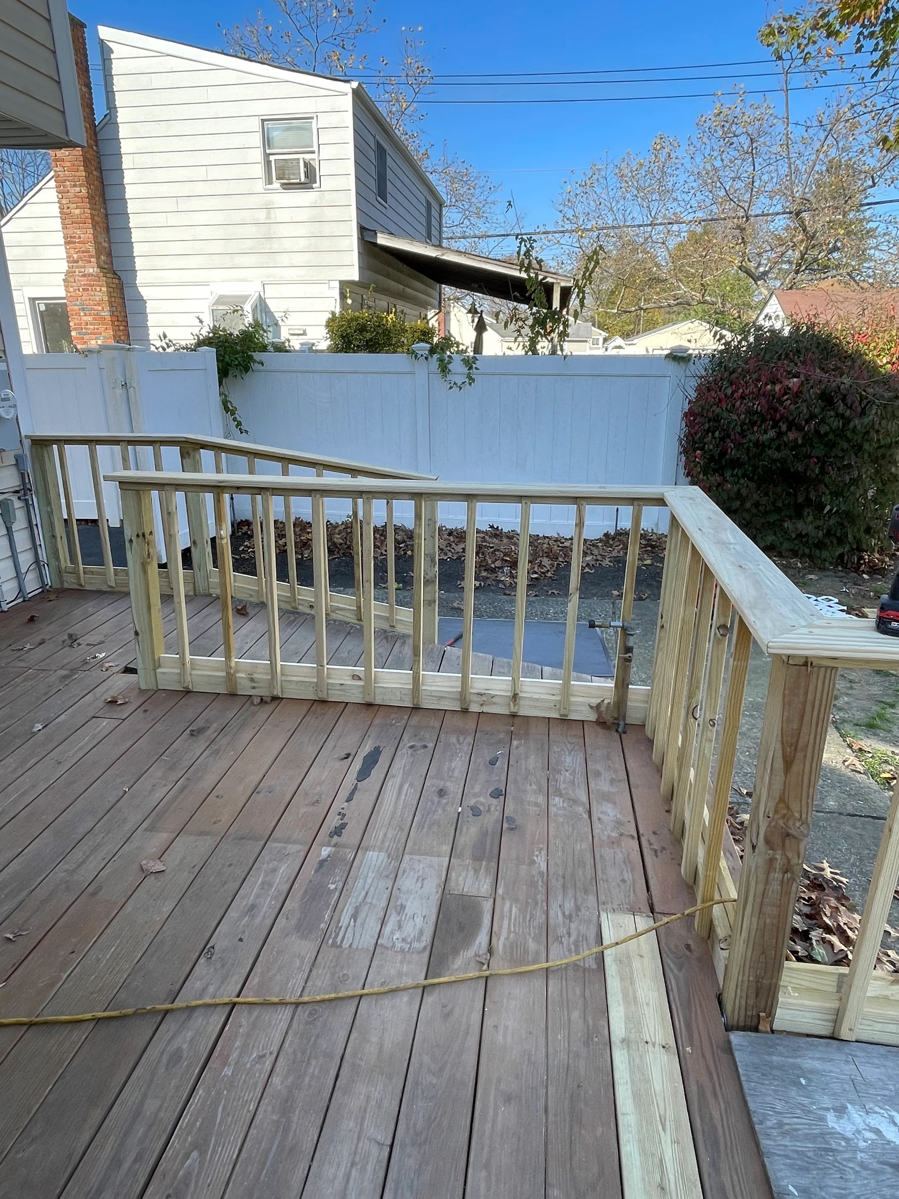 Newly constructed wooden deck with railings and bench seating overlooking backyard