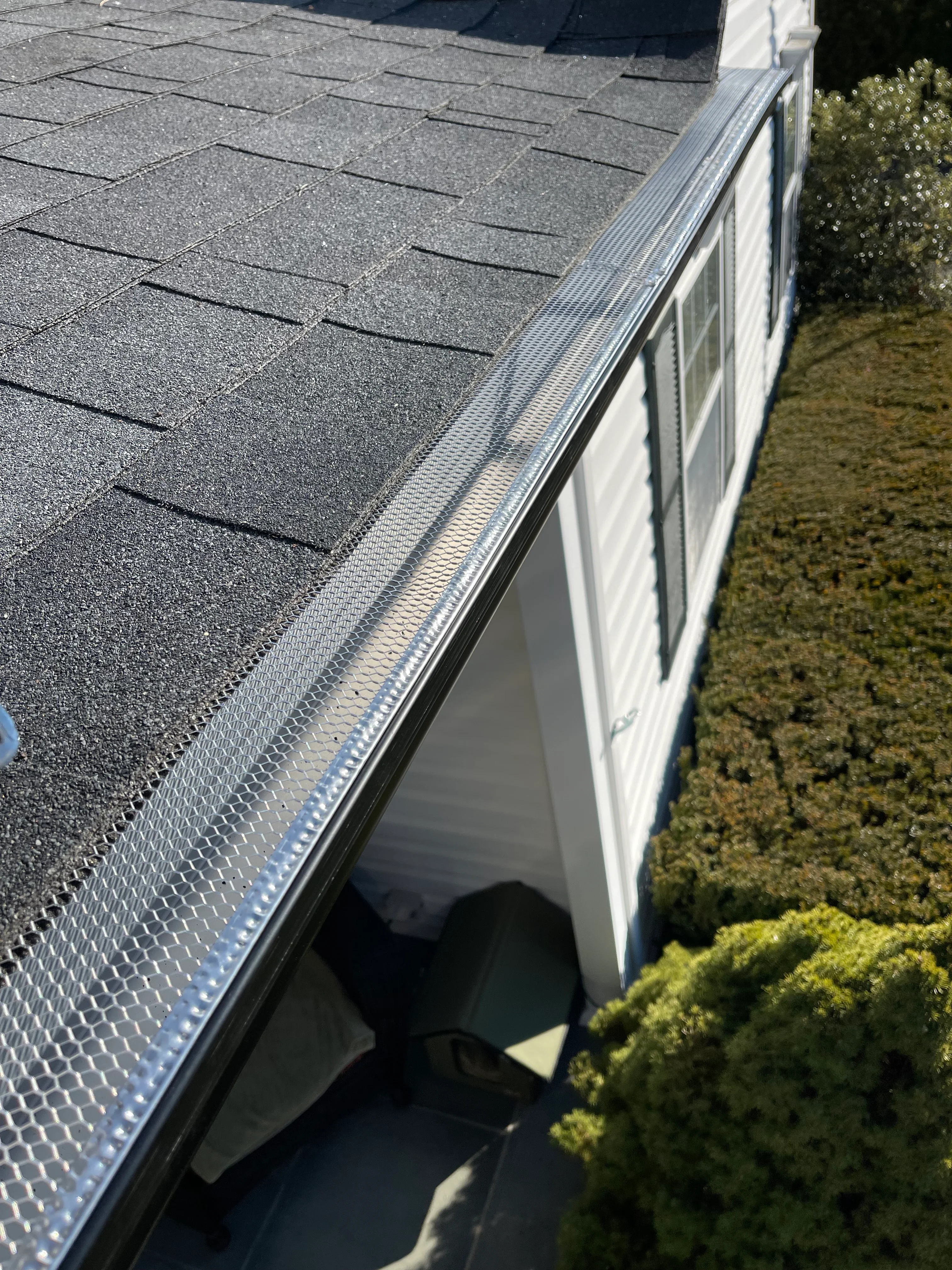 Gray architectural shingles with aluminum gutter system installed on residential roof