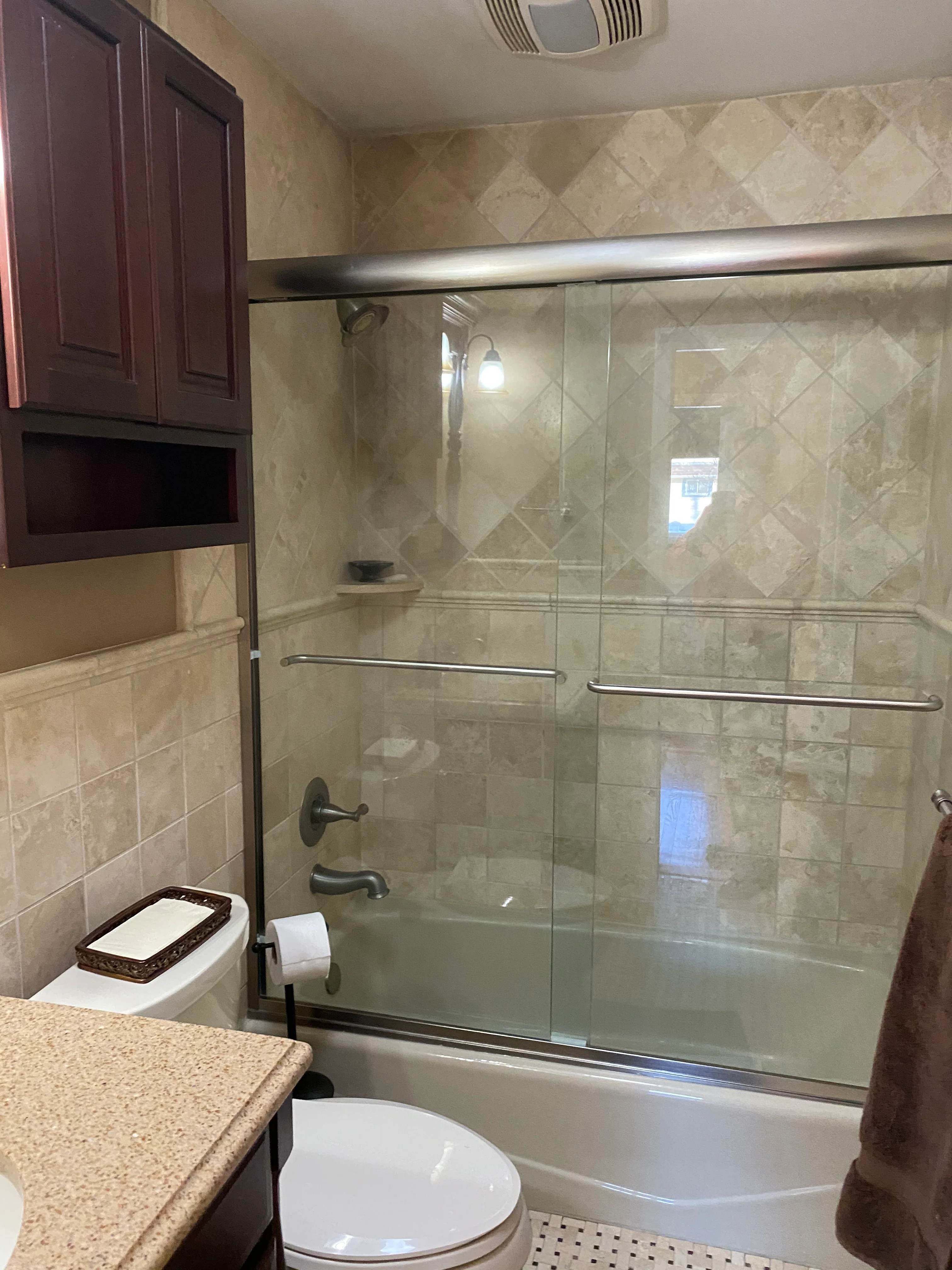 Modern bathroom with frameless glass shower enclosure and travertine tile walls