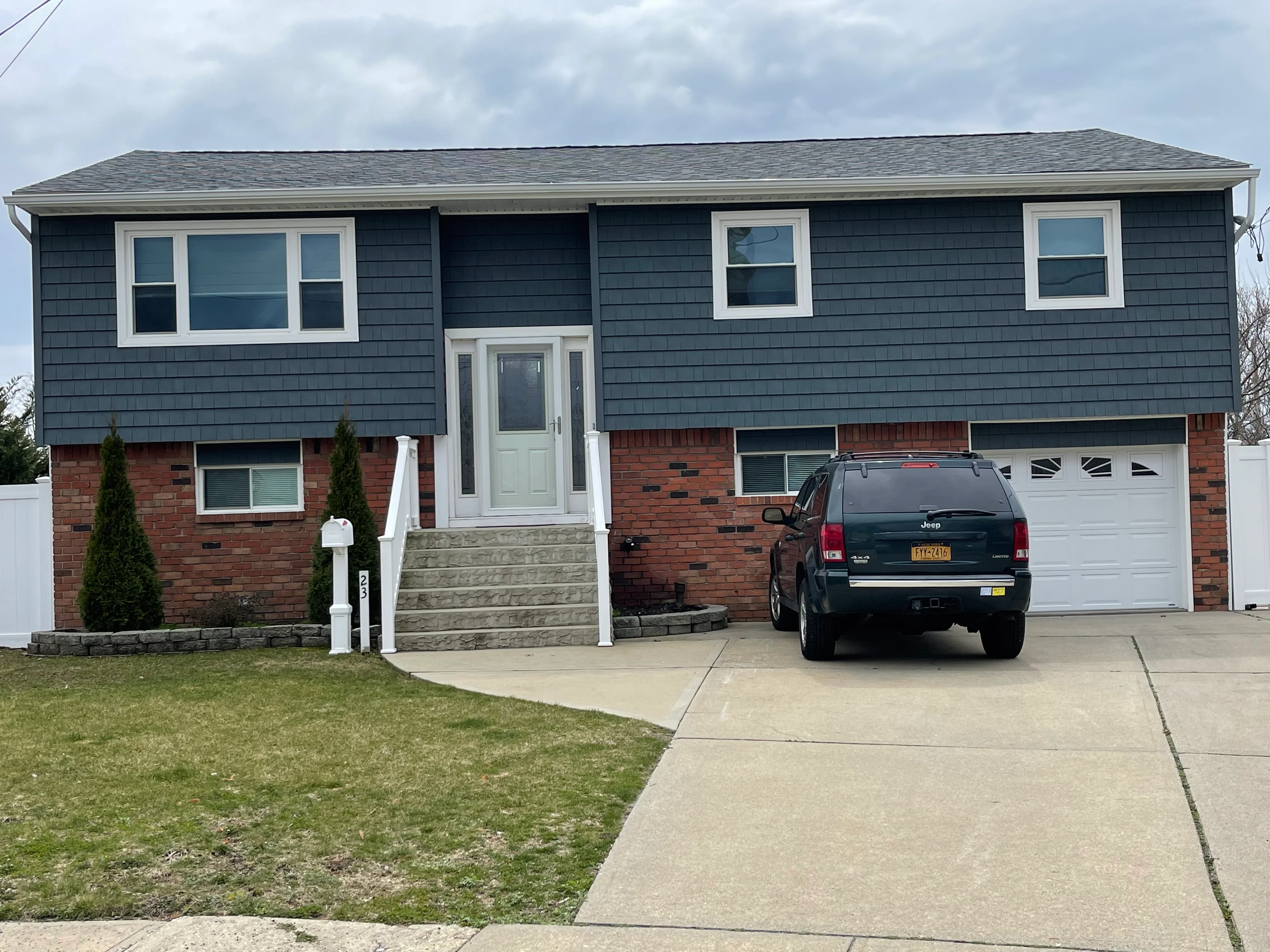 Split-level home with new blue siding, white trim windows, and brick lower level