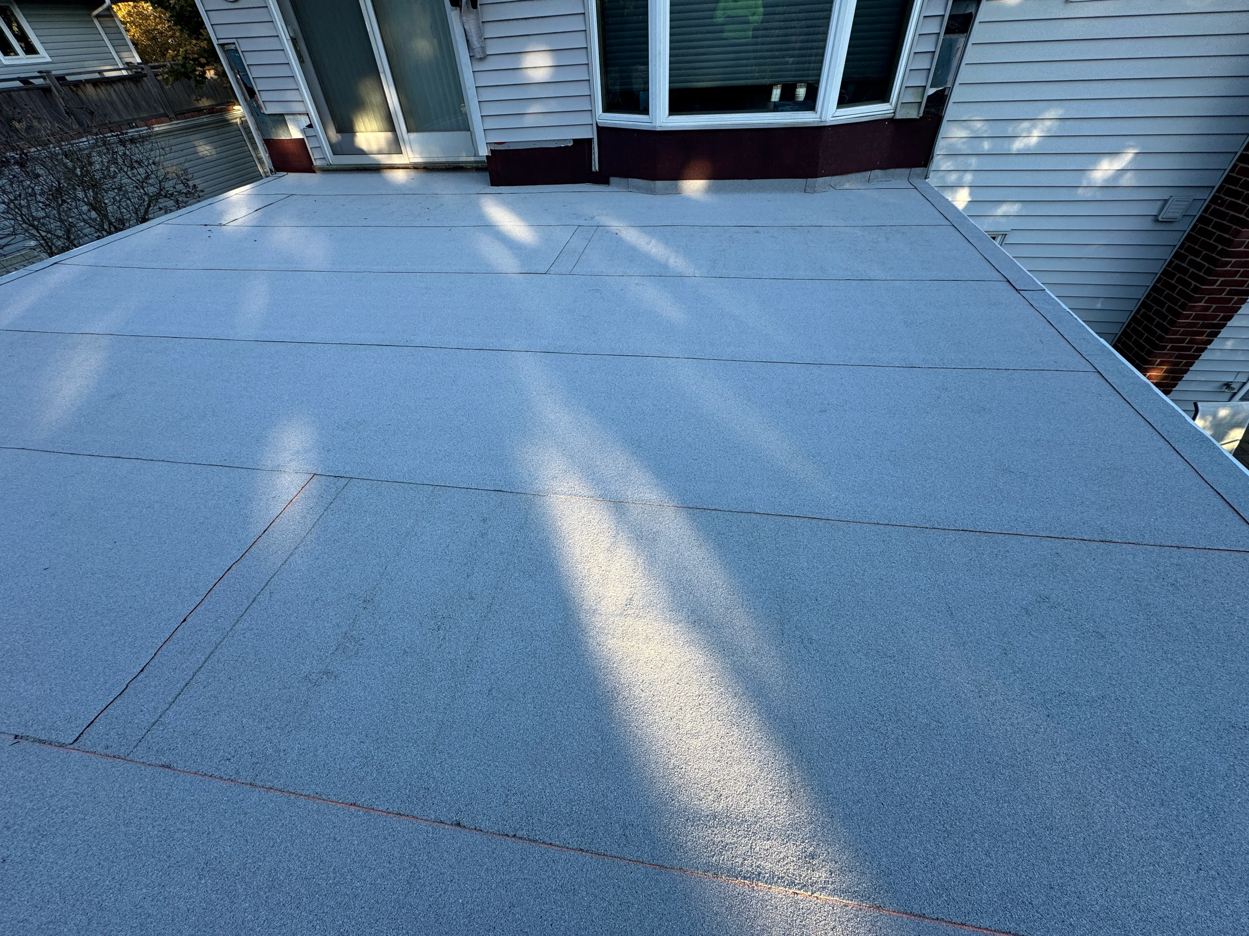 Light gray flat roof with clean seams installed on residential home in Lindenhurst