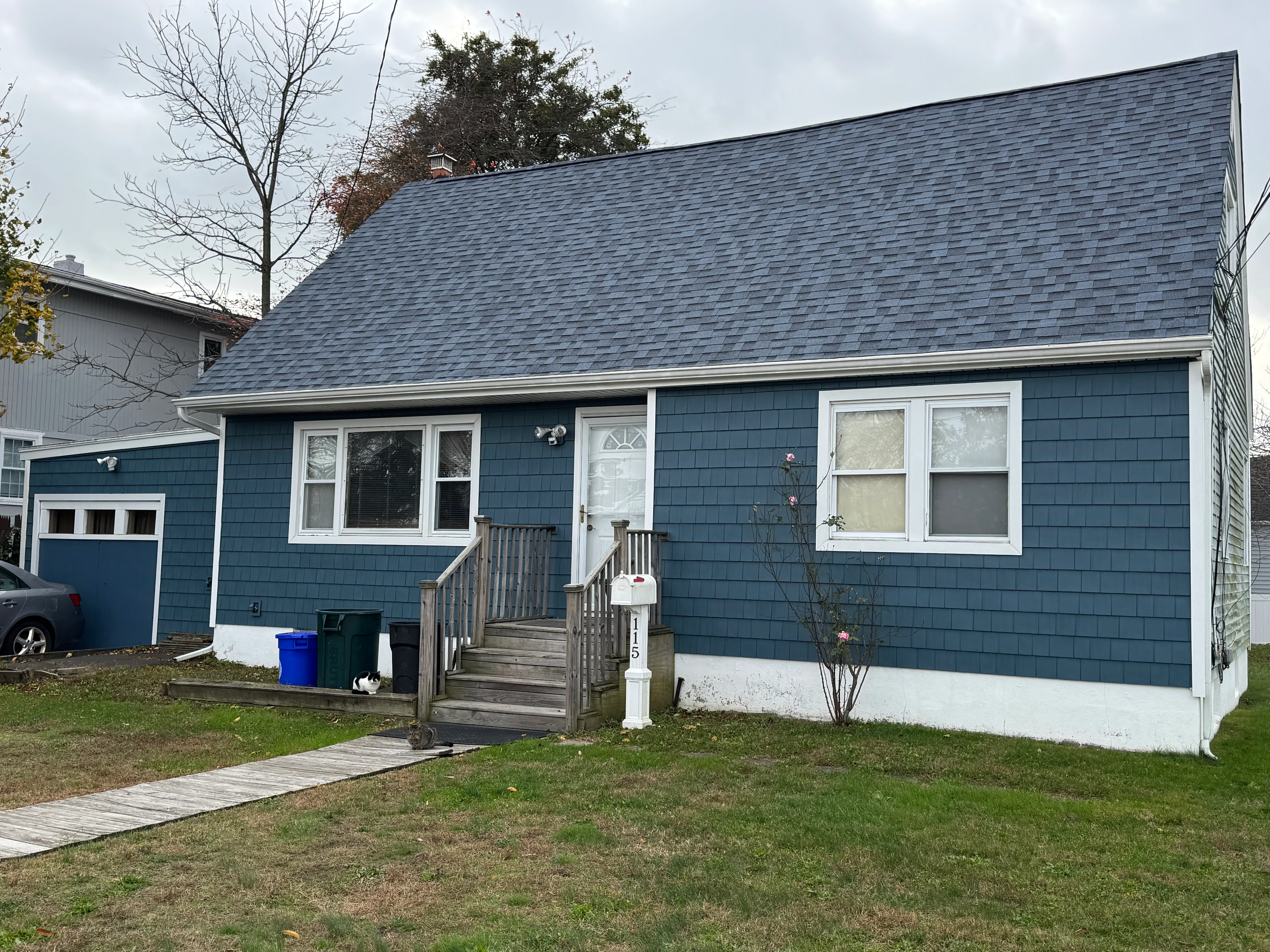 Blue ranch home with new siding, roof, windows, and front deck in Lindenhurst