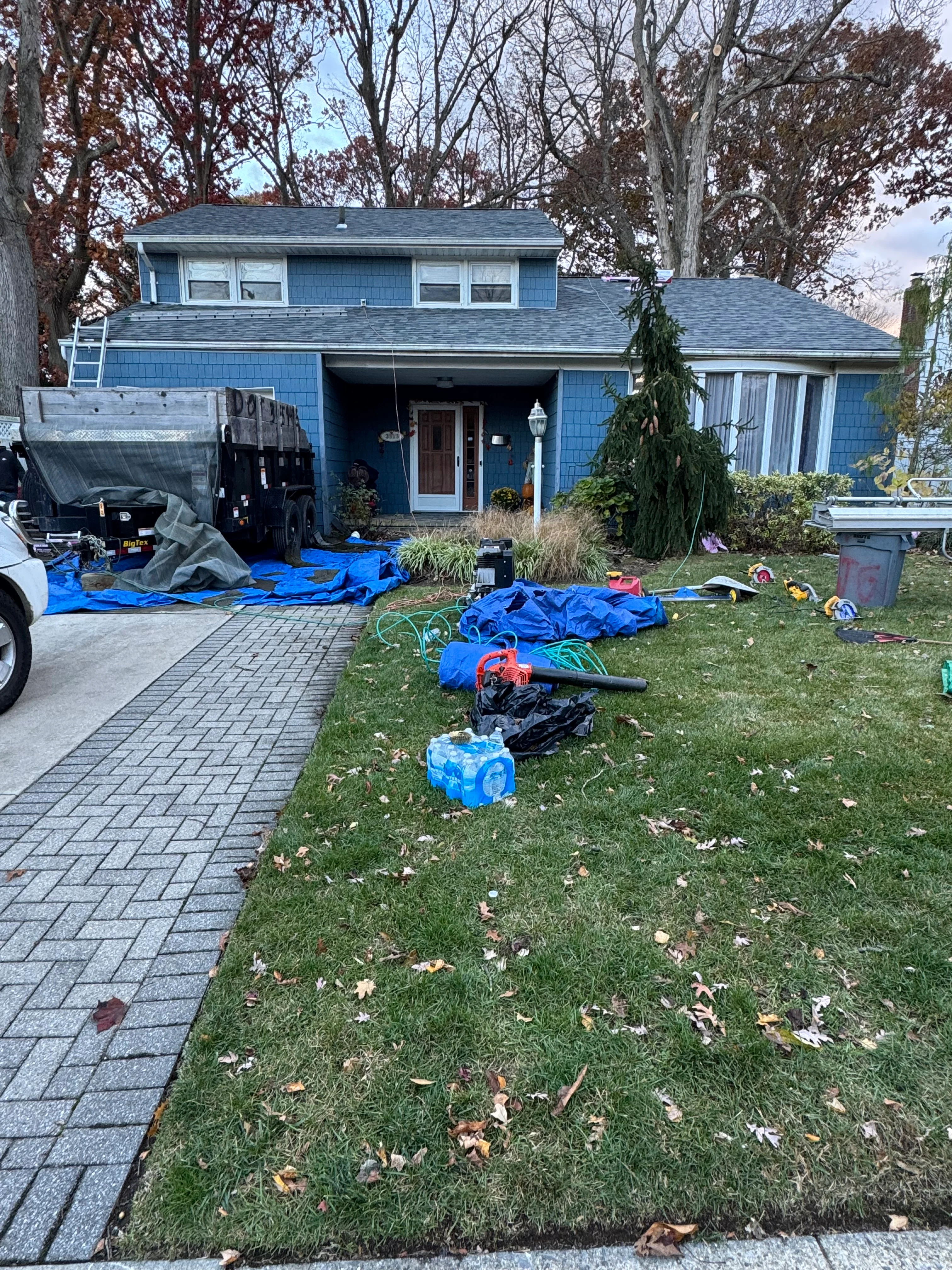 Two-story blue home with new gray asphalt shingle roof installation in progress