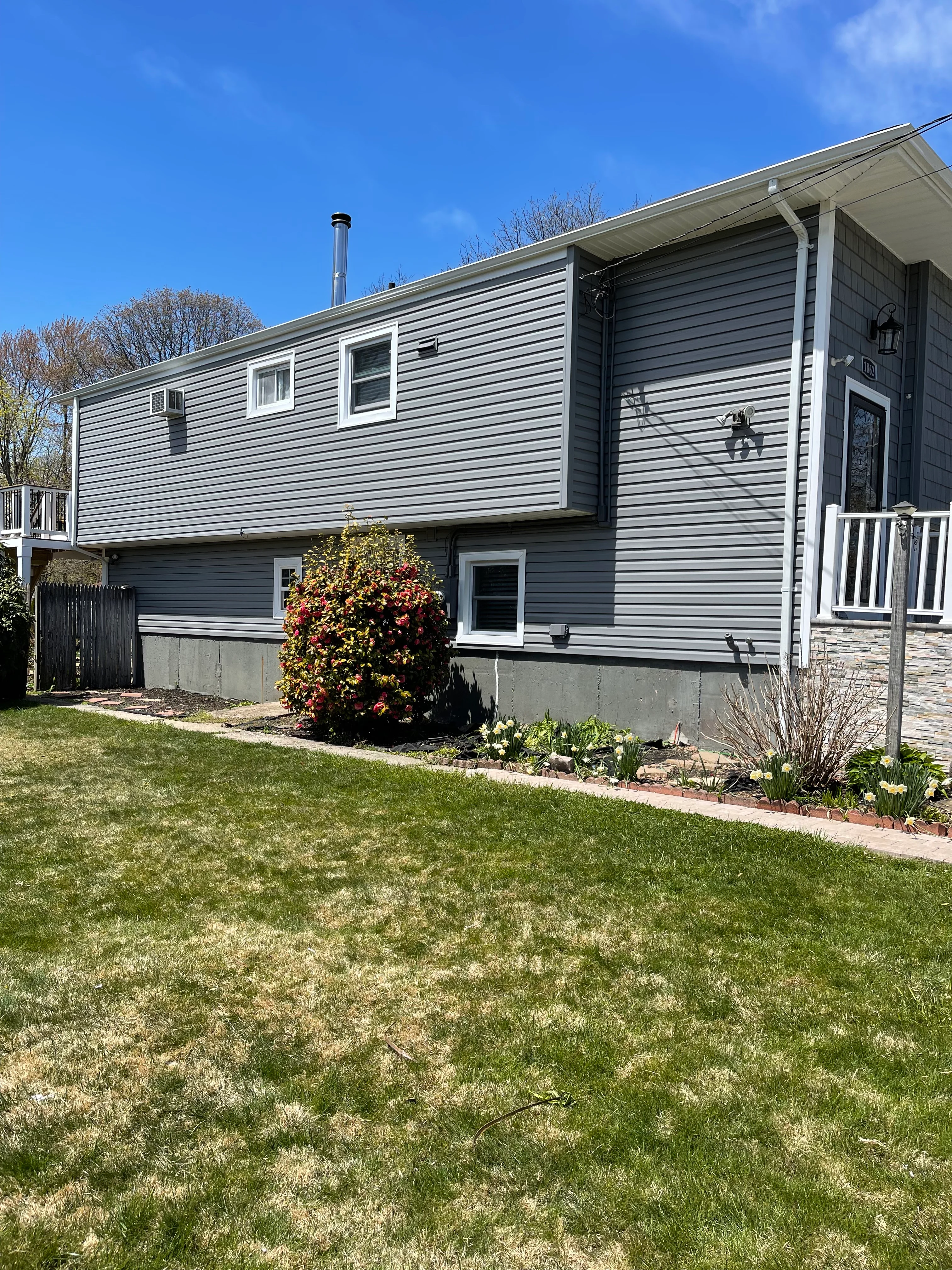Two-story home with new gray vinyl siding, white trim windows, and landscaped foundation beds
