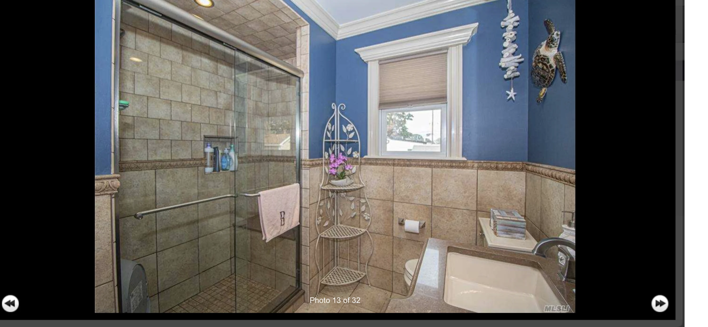 Modern bathroom with frameless glass shower, blue walls, and tile wainscoting