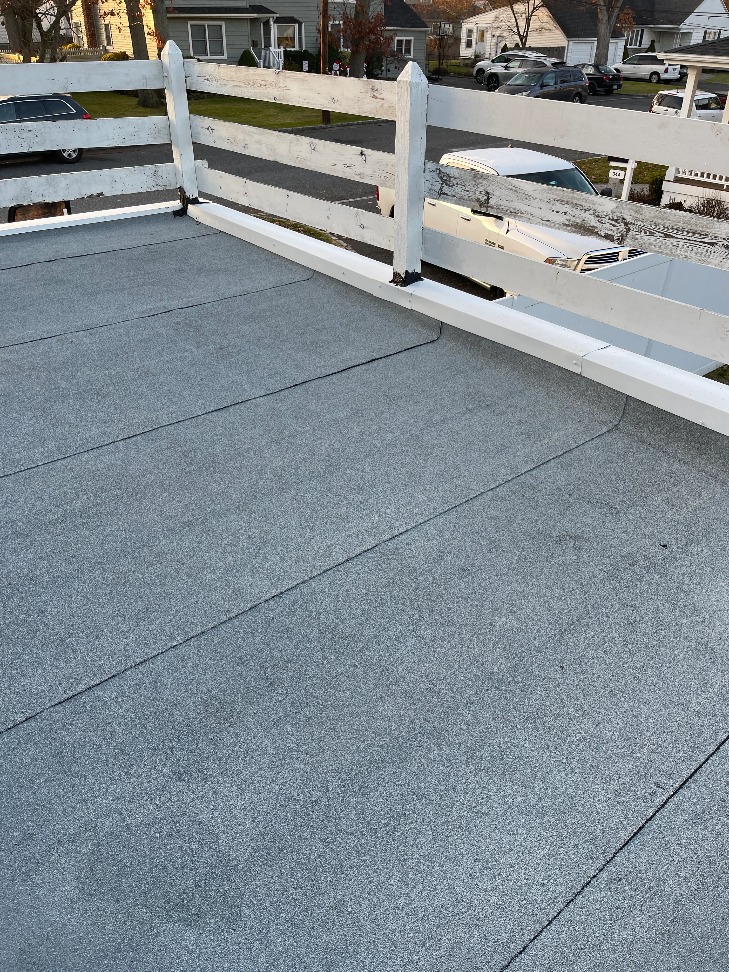 Gray flat roof with white trim and wooden railings on residential home