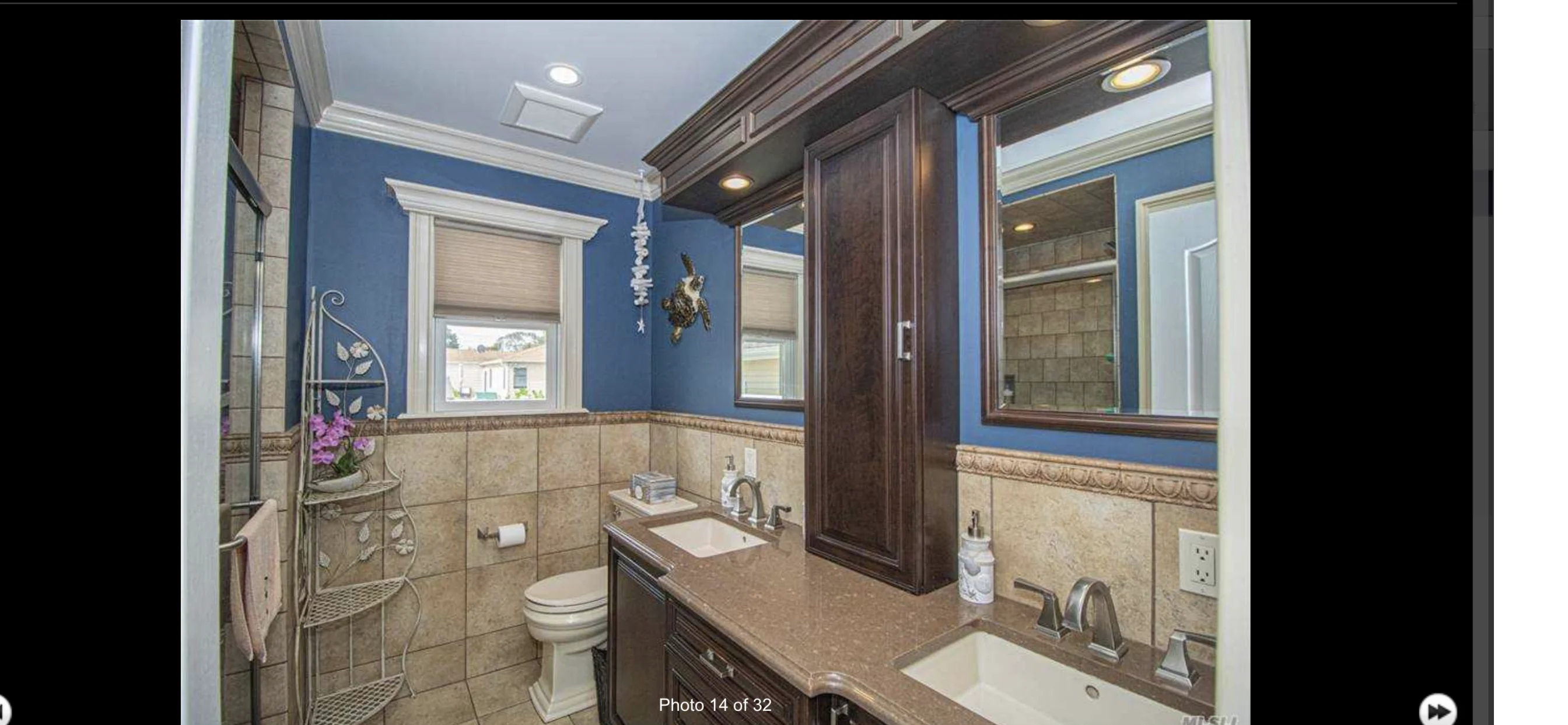 Luxury master bathroom with dual vanities, blue walls, and tile shower