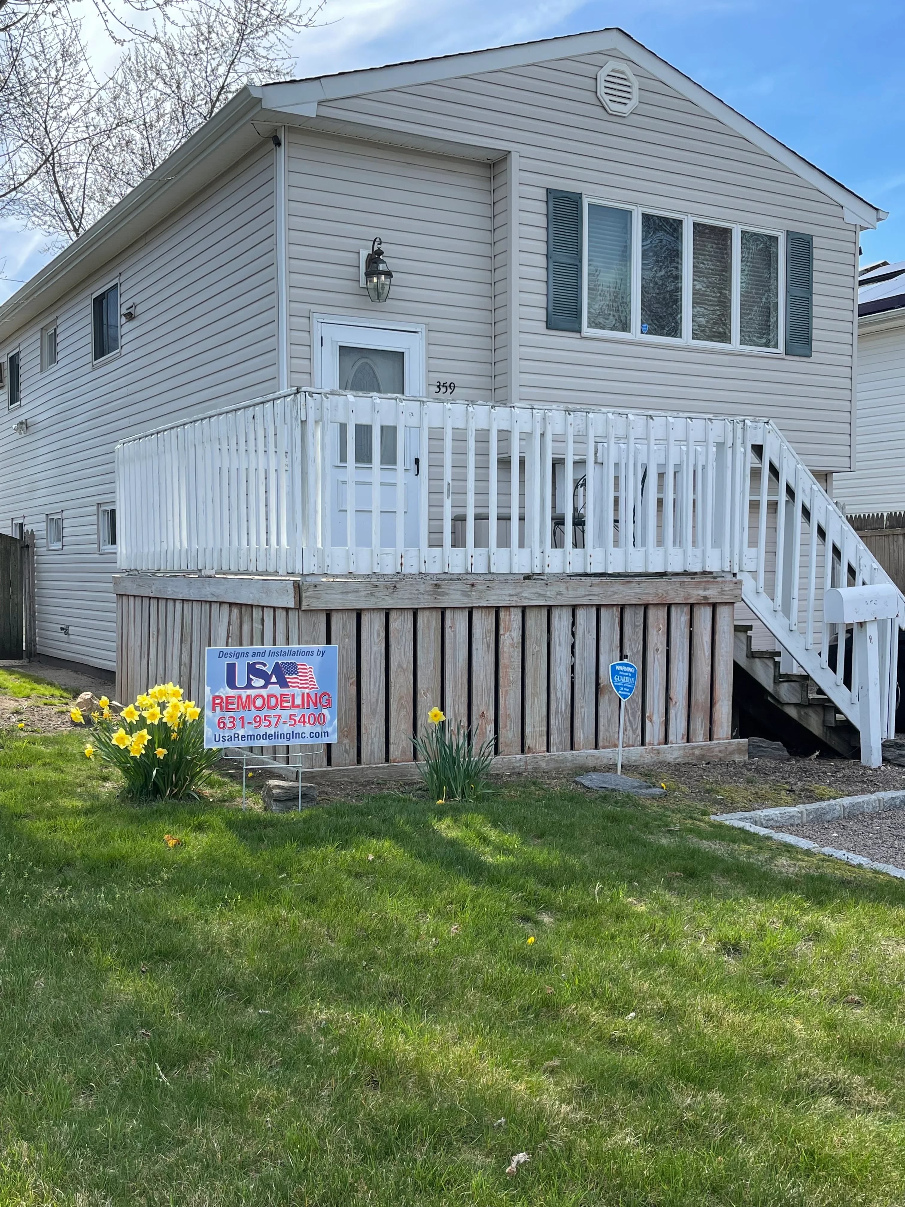 White aluminum deck railing installed on residential home with gray vinyl siding in Lindenhurst