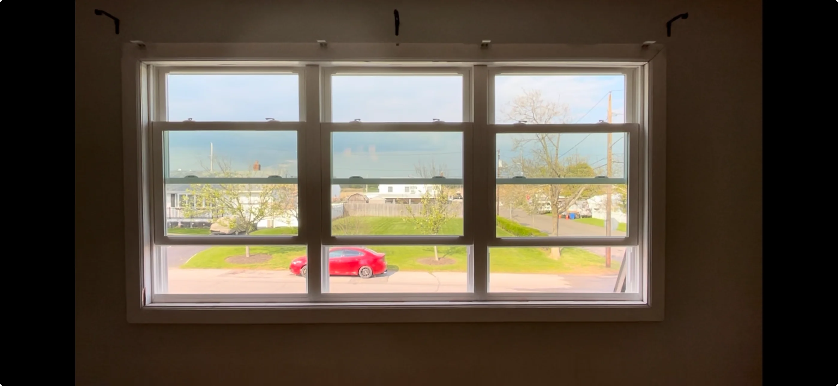 Triple picture window with nine panes showing residential driveway and landscape view
