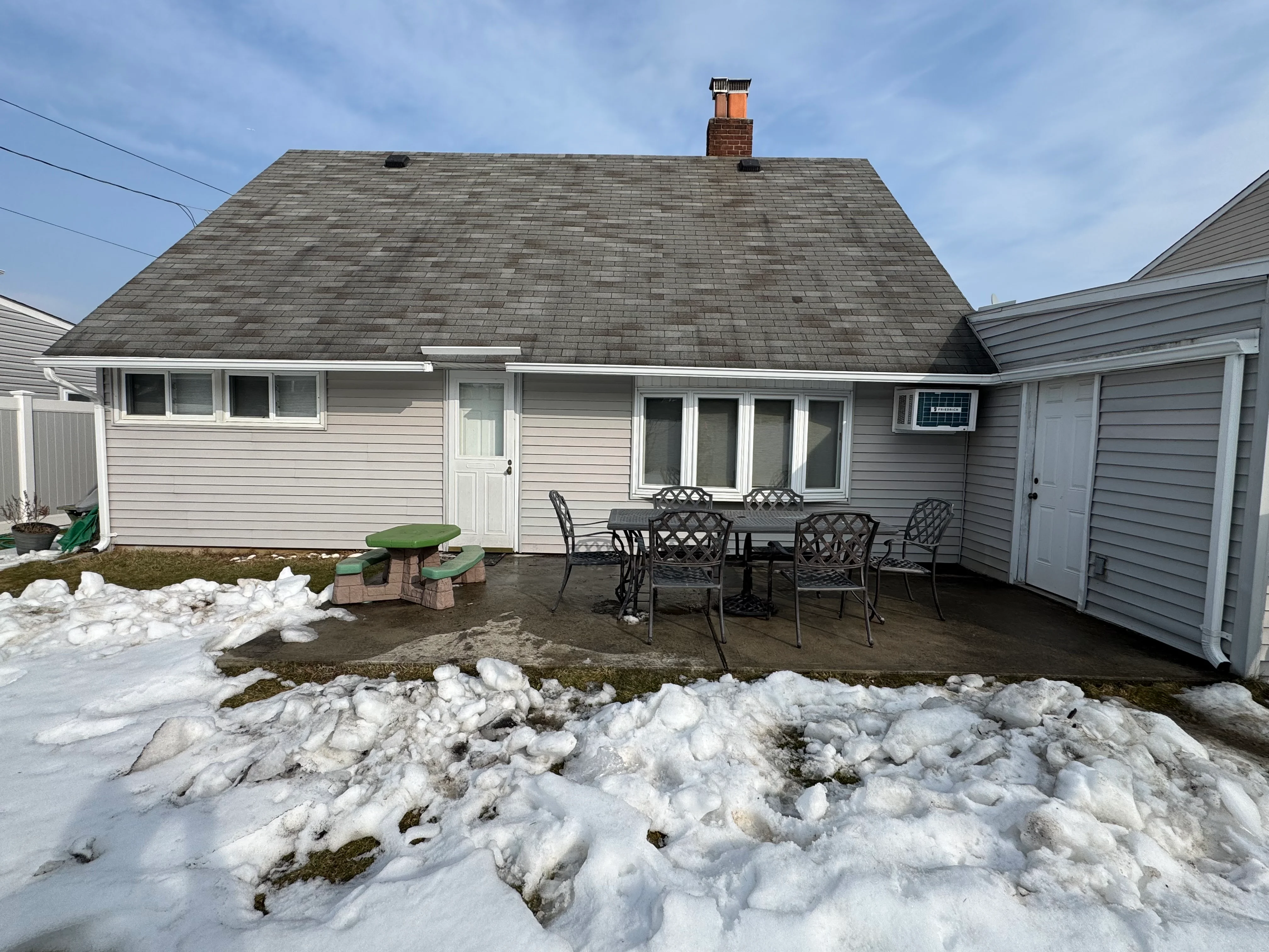 Residential home with new gray vinyl siding, dark shingle roof, and updated windows after renovation