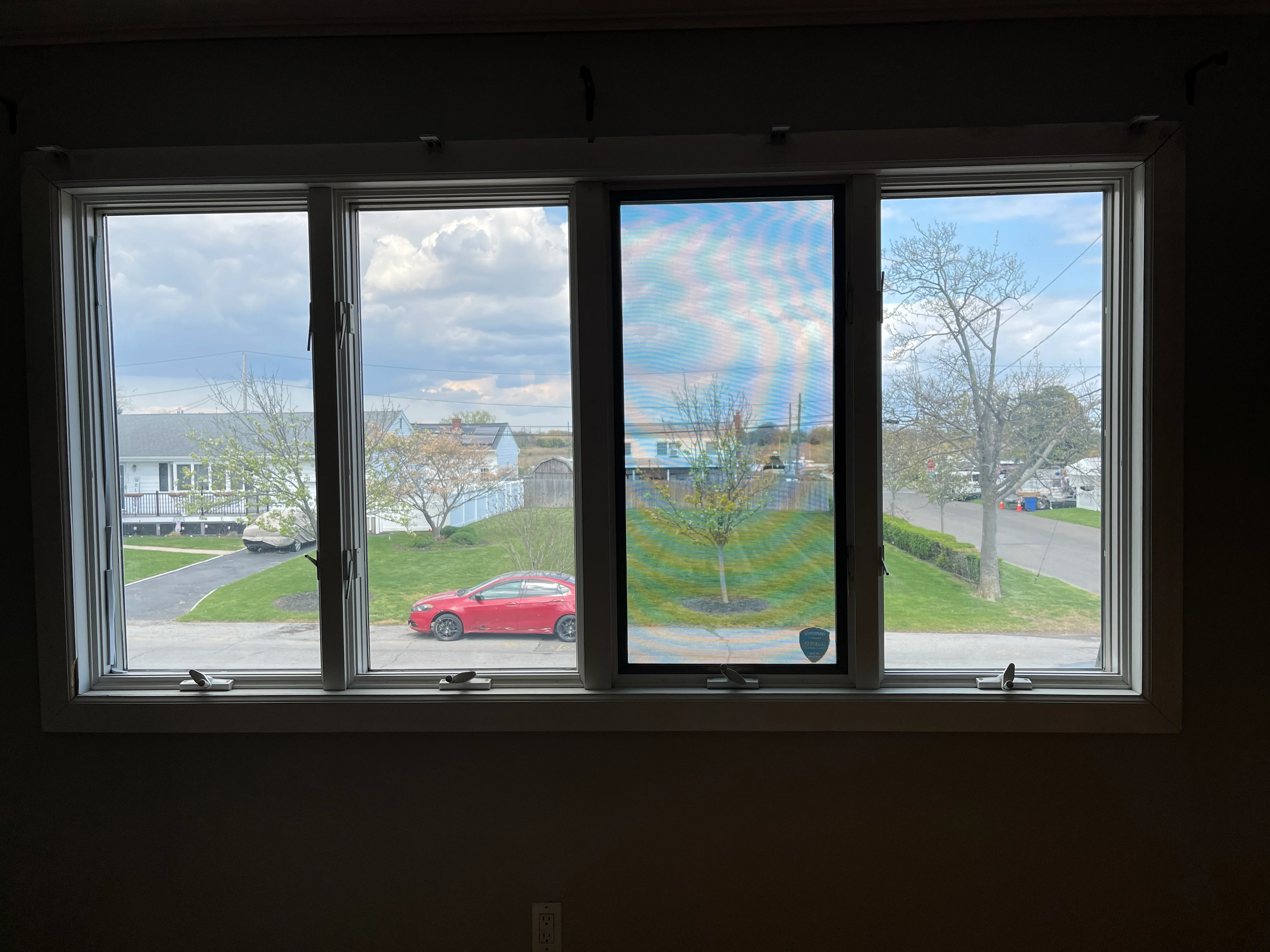 Four-panel casement windows with aluminum frames overlooking residential neighborhood and driveway