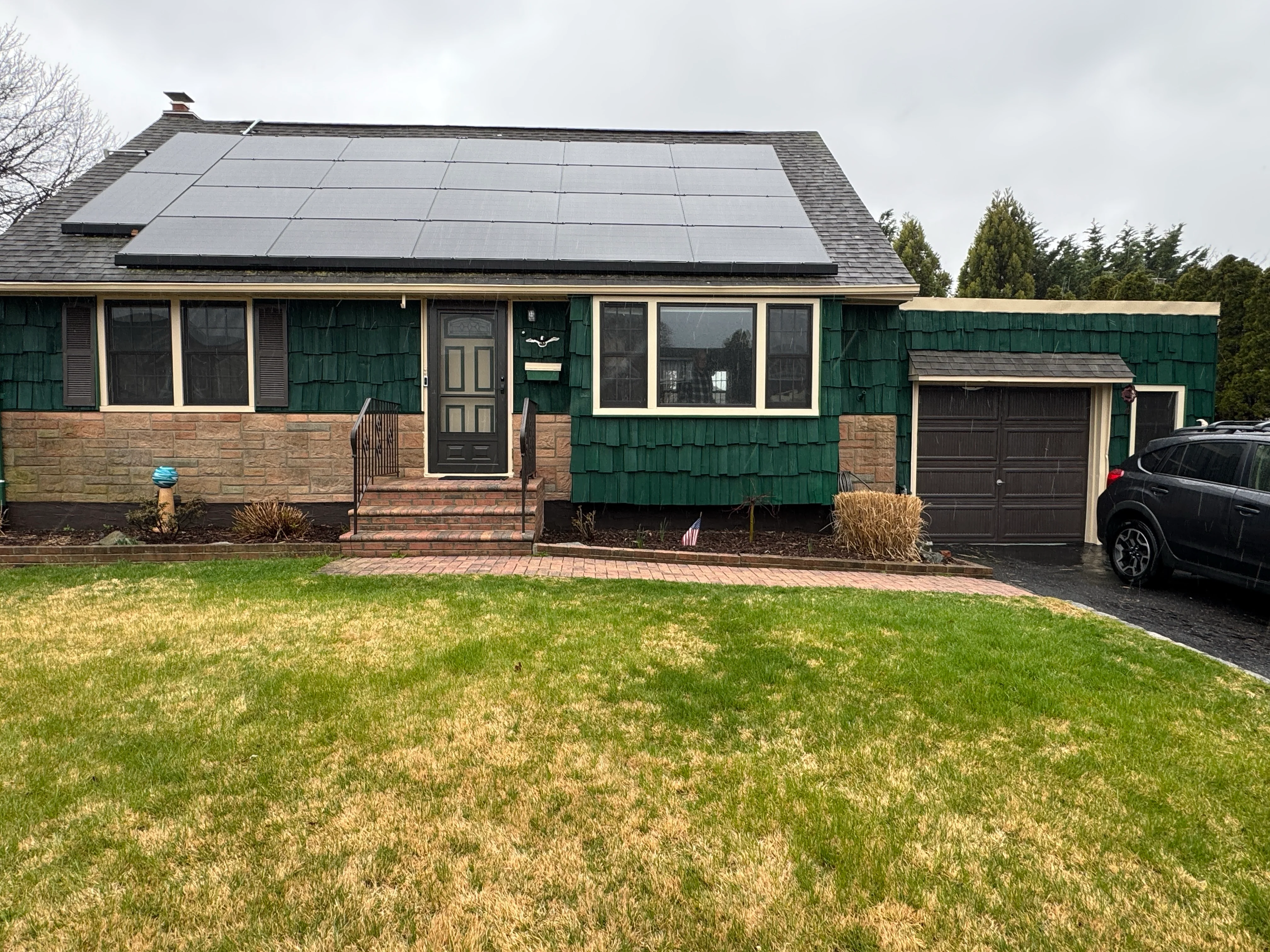 Home with newly installed solar panels on roof and green cedar shake siding